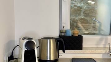 A kitchen with a kettle, a coffee maker, and a mat on the counter.