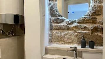 Bagno con parete in pietra, lavabo, specchio e water.