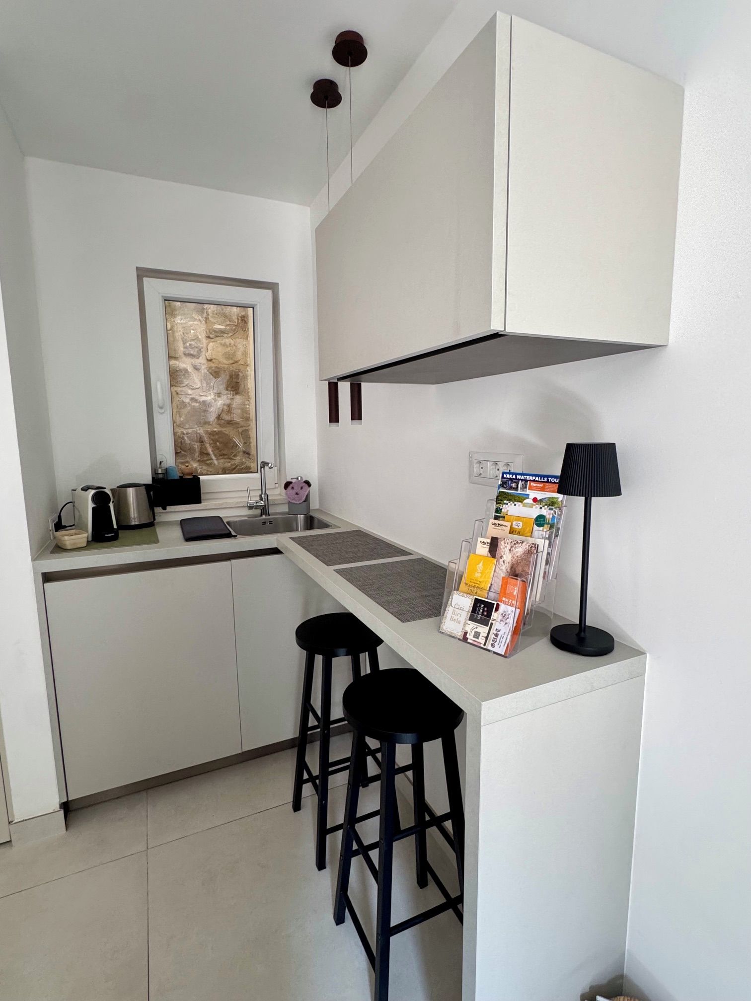 Cozinha compacta com fogão embutido, pia e um pequeno balcão com banquetas.