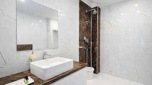 A modern bathroom with a large mirror, a white sink, a shower, and marble walls. - The Sea View Suites - Sea front, Pool & Breakfast (Puri)