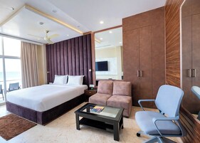 A hotel room with a large bed, a sofa, a coffee table, and a TV.