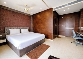 A bedroom with a bed, a desk, a chair, a ceiling fan, and a wardrobe.