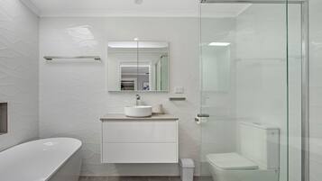 A modern bathroom with a freestanding bathtub, a glass-enclosed shower, and a white vanity with a sink and mirror.
