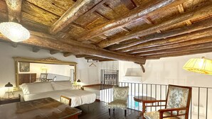 Una habitación rústica con vigas de madera a la vista, una cama, una silla y una mesa.