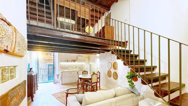 Amplia sala de estar con escalera, mesa de comedor y sofá.