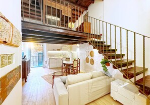A spacious living area with a staircase, a dining table, and a sofa. - Solemar Sicilia - Casa Enrica (Palermo)