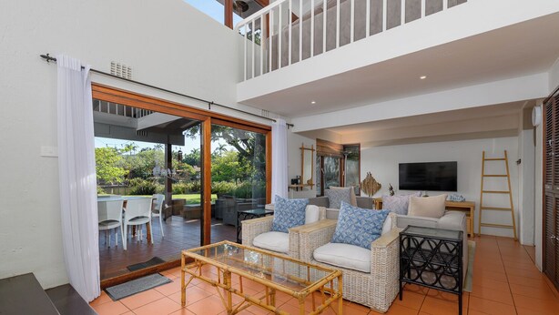 A spacious living area with a balcony, wicker furniture, and a TV.