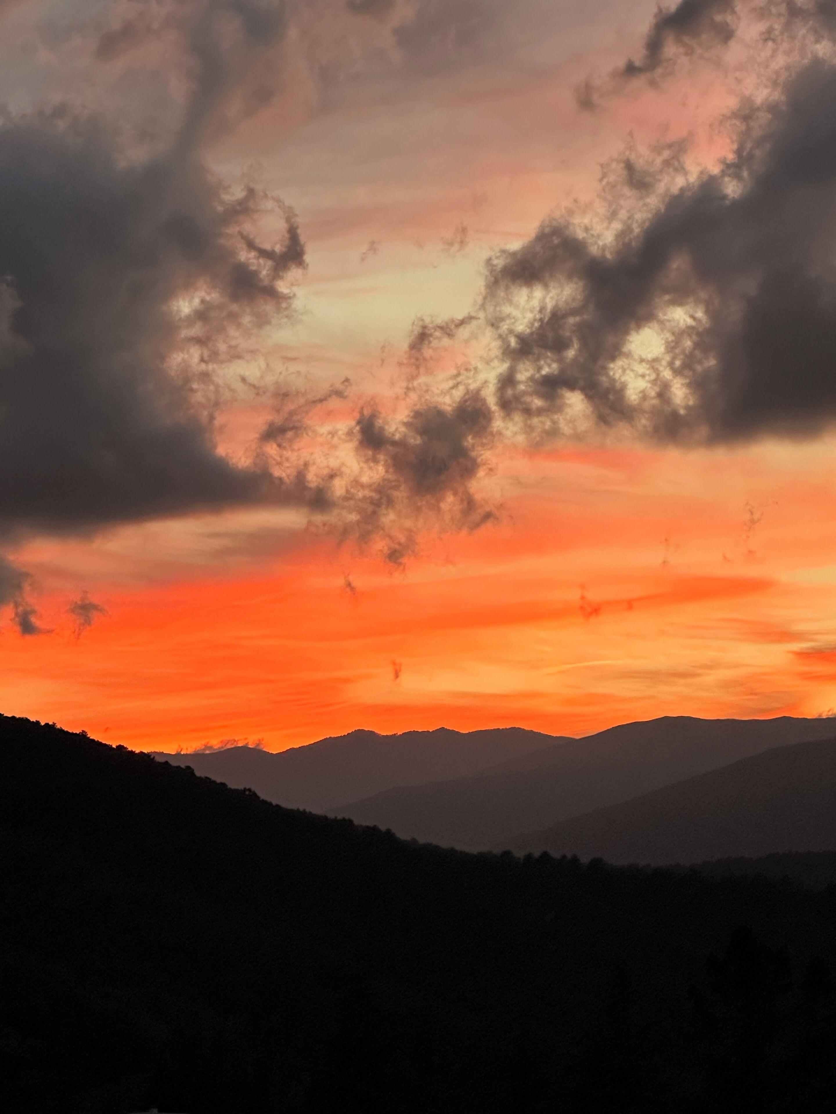 A sunset over a mountain range with clouds.