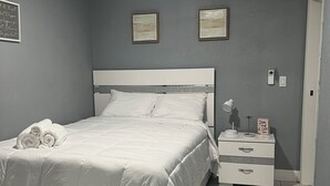 A neatly arranged bedroom with a bed, bedside tables, and a wall-mounted air conditioner. - Cozy Haven Apartment (Winter Haven)