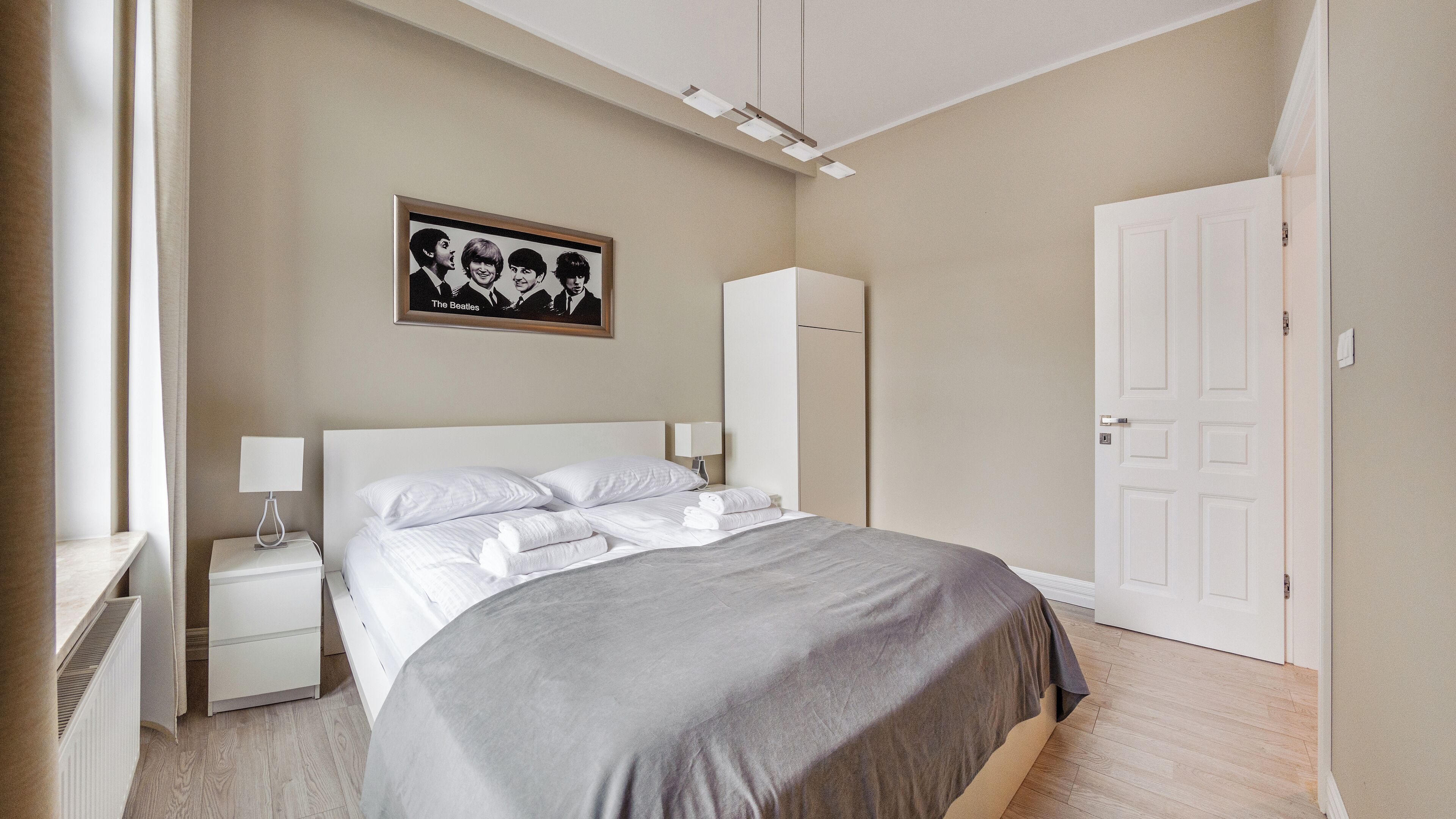 A bedroom with a bed, nightstands, a wardrobe, and a framed picture on the wall.