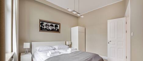 A bedroom with a bed, nightstands, a wardrobe, and a framed picture on the wall.