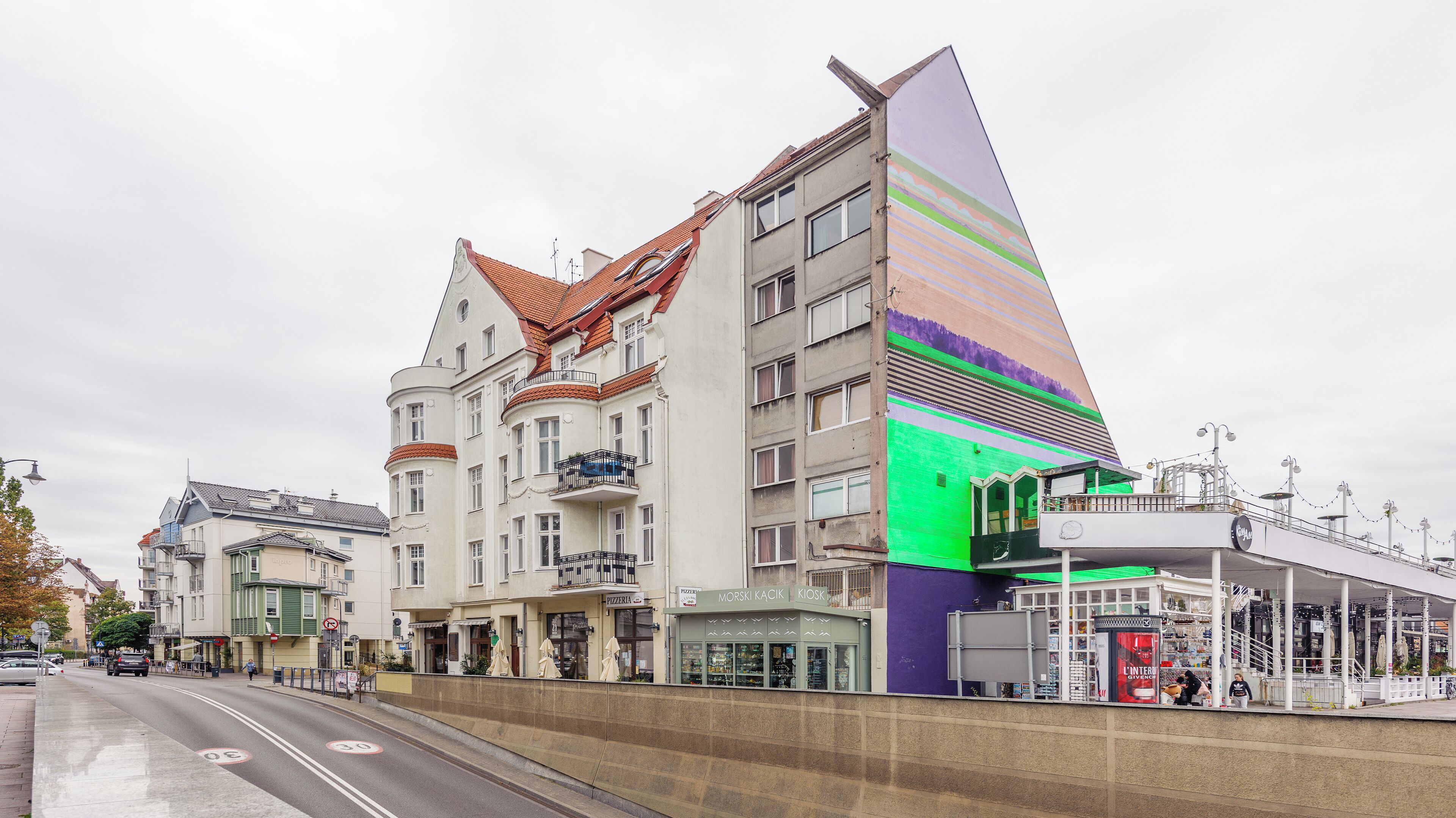 A multi-story building with a distinctive sloped roof and a colorful facade.