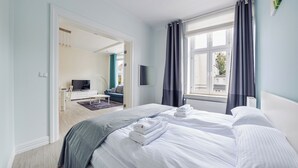 Ett hotellrum med en säng, en tv, en soffa och ett fönster med gardiner.