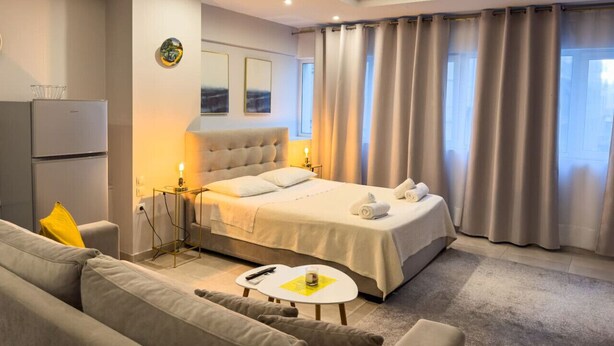 A modern hotel room with a large bed, a sofa, a small table, and a ceiling light. - Glamorous & Spacious Renovated Apartment, Syntagma (Athina)