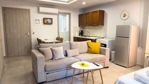 A modern living room with a sofa, a small table, and a kitchen area with cabinets and appliances. - Glamorous & Spacious Renovated Apartment, Syntagma (Athina)