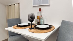 A dining table with two plates, two glasses, and bottles of liquor.