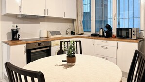A modern kitchen with white cabinets, a wooden countertop, and a dining table with chairs. - Nikitara Nook-Close to Metro and Train (Athina)