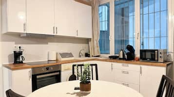 A modern kitchen with white cabinets, a wooden countertop, and a dining table with chairs.