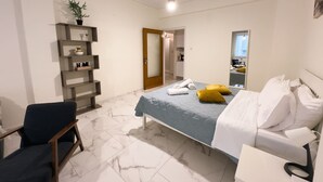 A bedroom with a bed, a chair, a shelf with decorative items, and a mirror. - Nikitara Nook-Close to Metro and Train (Athina)