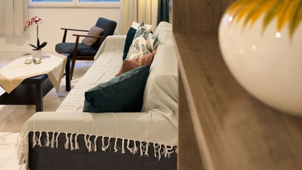 A modern living room with a sofa, a chair, a small table, and a lamp. - Nikitara Nook-Close to Metro and Train (Athina)