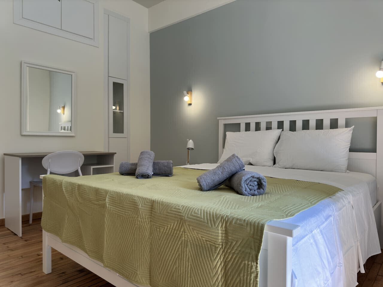 A neatly arranged bedroom with a bed, a desk, and a chair.