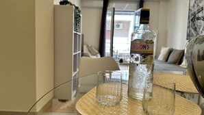 Ein modernes Wohnzimmer mit einem Glastisch, einer Spirituosenflasche und zwei Gläsern.