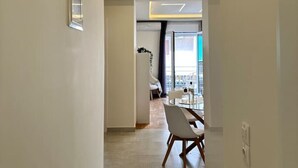 Ein moderner, minimalistisch gestalteter Flur mit Essbereich, Tisch und Stühlen, einem gerahmten Bild an der Wand und einer sichtbaren Türnummer.