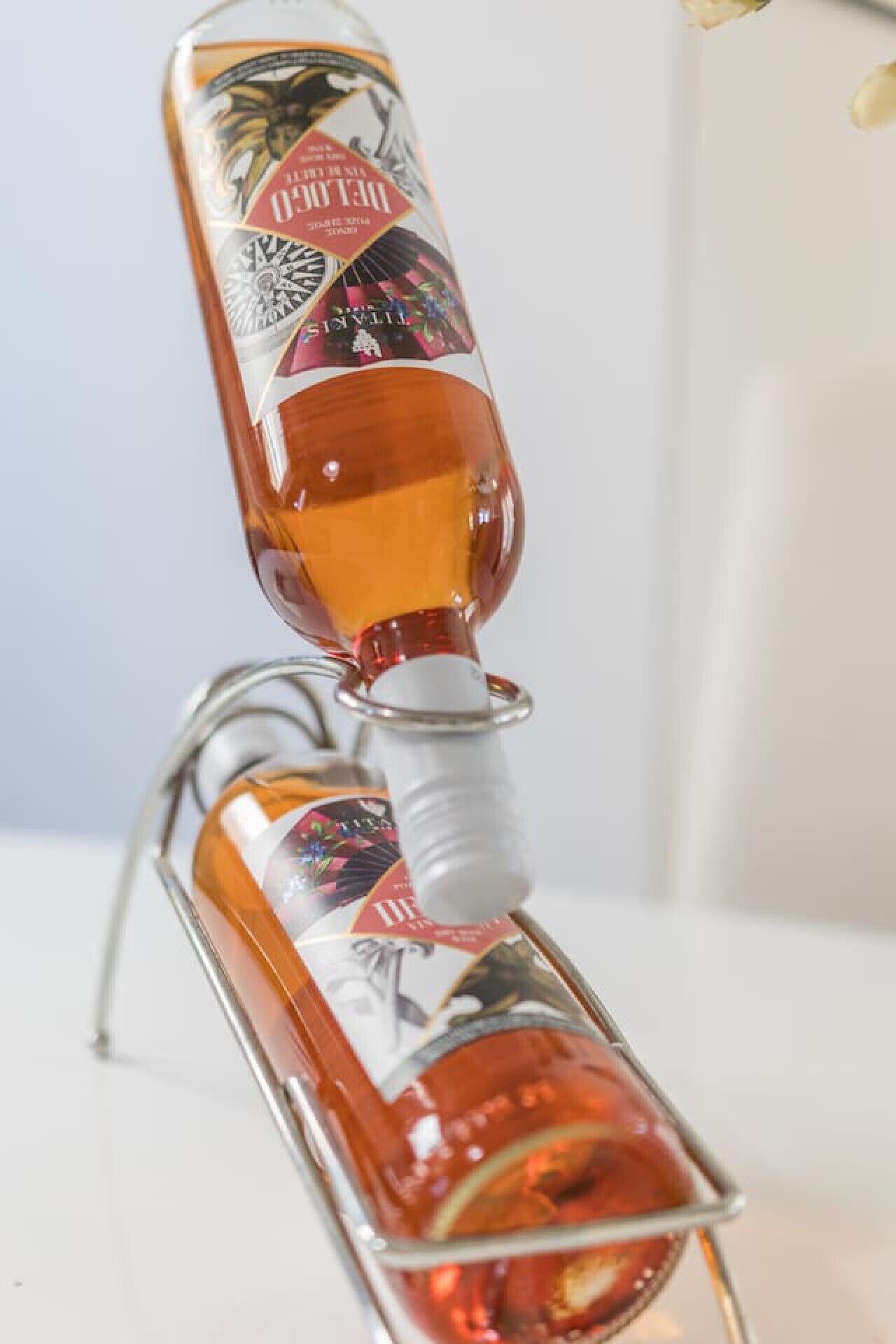 Uma garrafa de bebida alcoólica com etiqueta decorativa, apoiada em um suporte de metal.