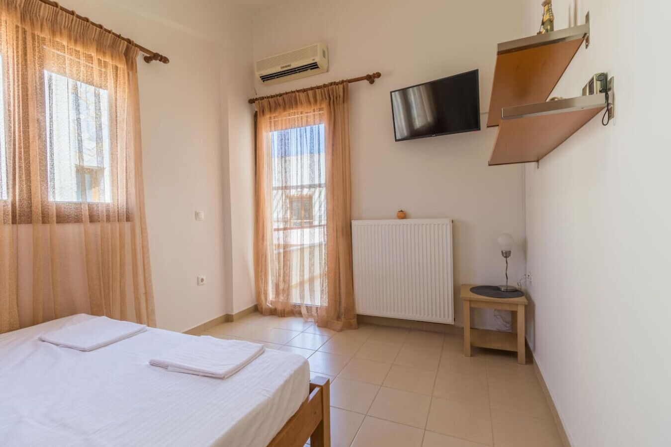 Una habitación con cama, radiador, televisor y una mesita.