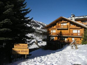 Een houten chalet met een balkon, omgeven door met sneeuw bedekte bergen.