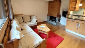 Un salon avec un canapé, un tapis rouge, une cheminée et des meubles en bois.
