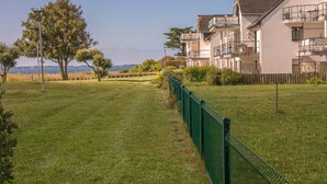 En gång som leder till en bostadsbyggnad med flera balkonger och utsikt över havet.