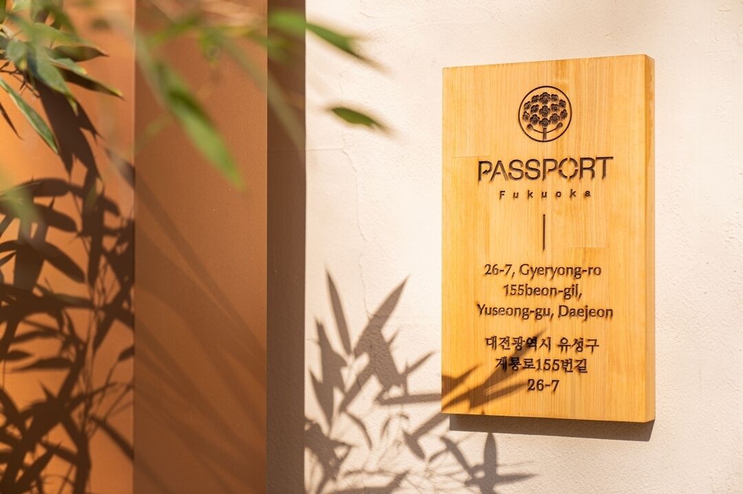 A wooden sign with the text "PASSPORT FUKUOKA" and an address in Korean.