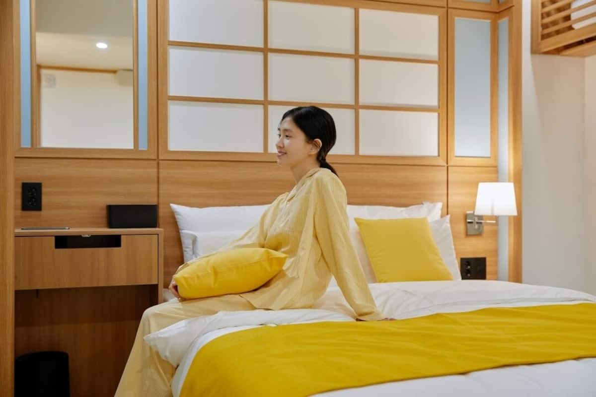 A hotel room with a bed, a nightstand, a lamp, and a wooden headboard.