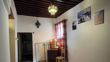 Une pièce comprenant un lit, un bureau avec une chaise, un luminaire suspendu et un tapis à motifs.