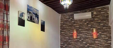 A bedroom with two beds, a wooden ceiling, a stone wall, and a chandelier.