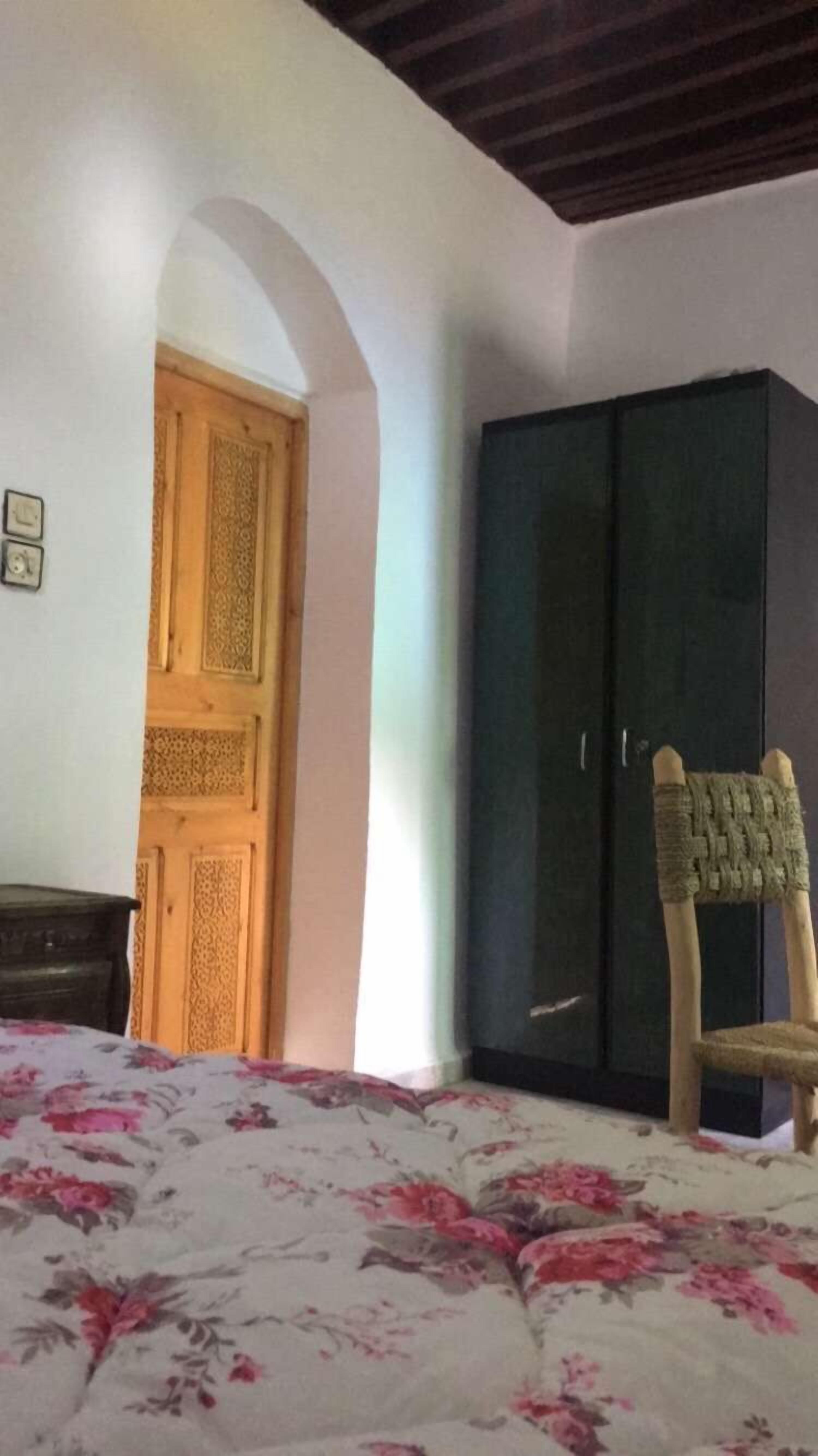 Een slaapkamer met een bed, een kledingkast en een stoel.