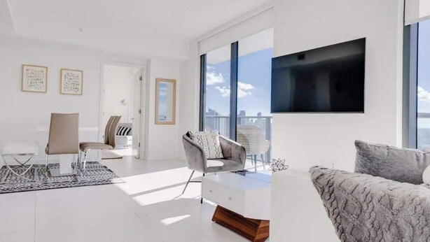 Una sala de estar moderna con un sofá, una silla, una mesa de centro y un televisor montado en la pared.