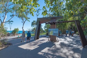 Entrada a un parque con un arco de madera y señalización informativa.