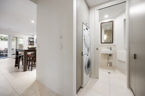 Un lavadero con lavadora y secadora, un lavabo y un espejo.
