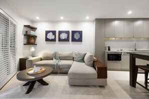 A modern living room with a sofa, coffee table, and artwork on the wall. - Coastal Serenity at Little Cove (Noosa)