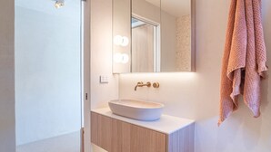 Un baño moderno con un espejo grande, un lavabo blanco y una toalla colgada en la pared.