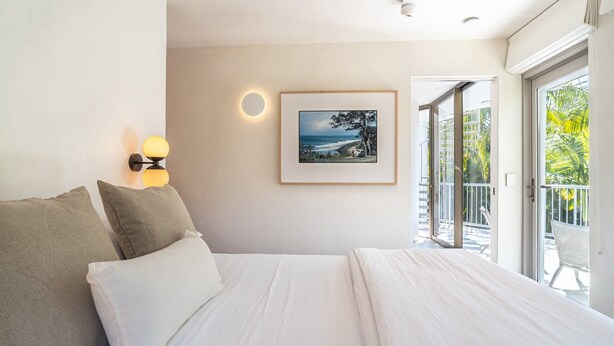 Un dormitorio con cama, un cuadro en la pared y un balcón con vistas.