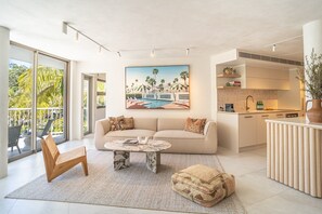 Un salon moderne avec un canapé, une table basse et un tableau représentant une scène de plage.