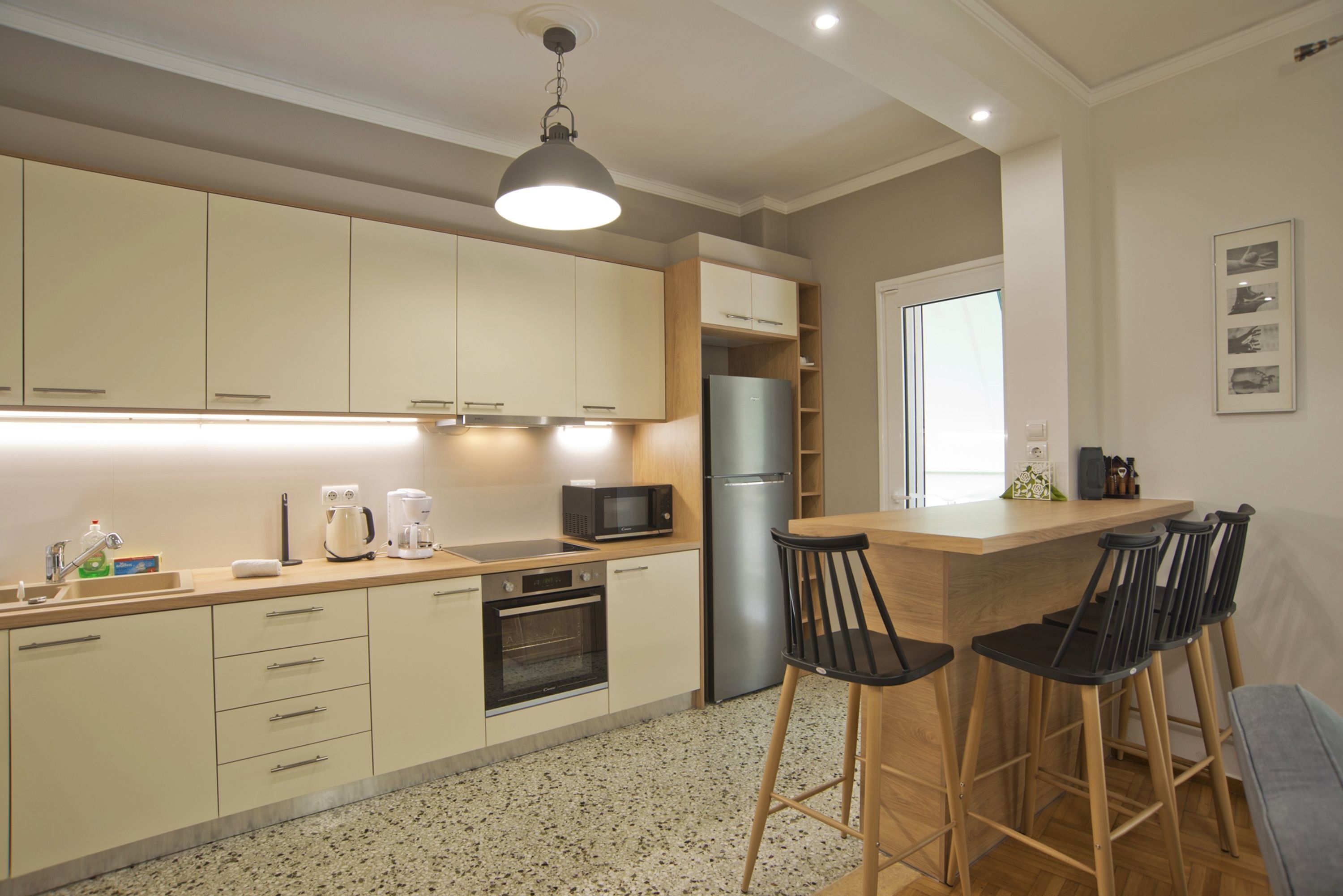 A modern kitchen with a central island, bar stools, and a microwave.