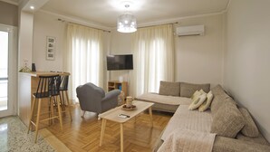 Ein Wohnzimmer mit einer Couch, einem Couchtisch, einem Fernseher und einer Bar mit Sesseln.