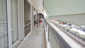 Ein Balkon mit Blick auf eine Straße, ein Stuhl und ein Tisch.