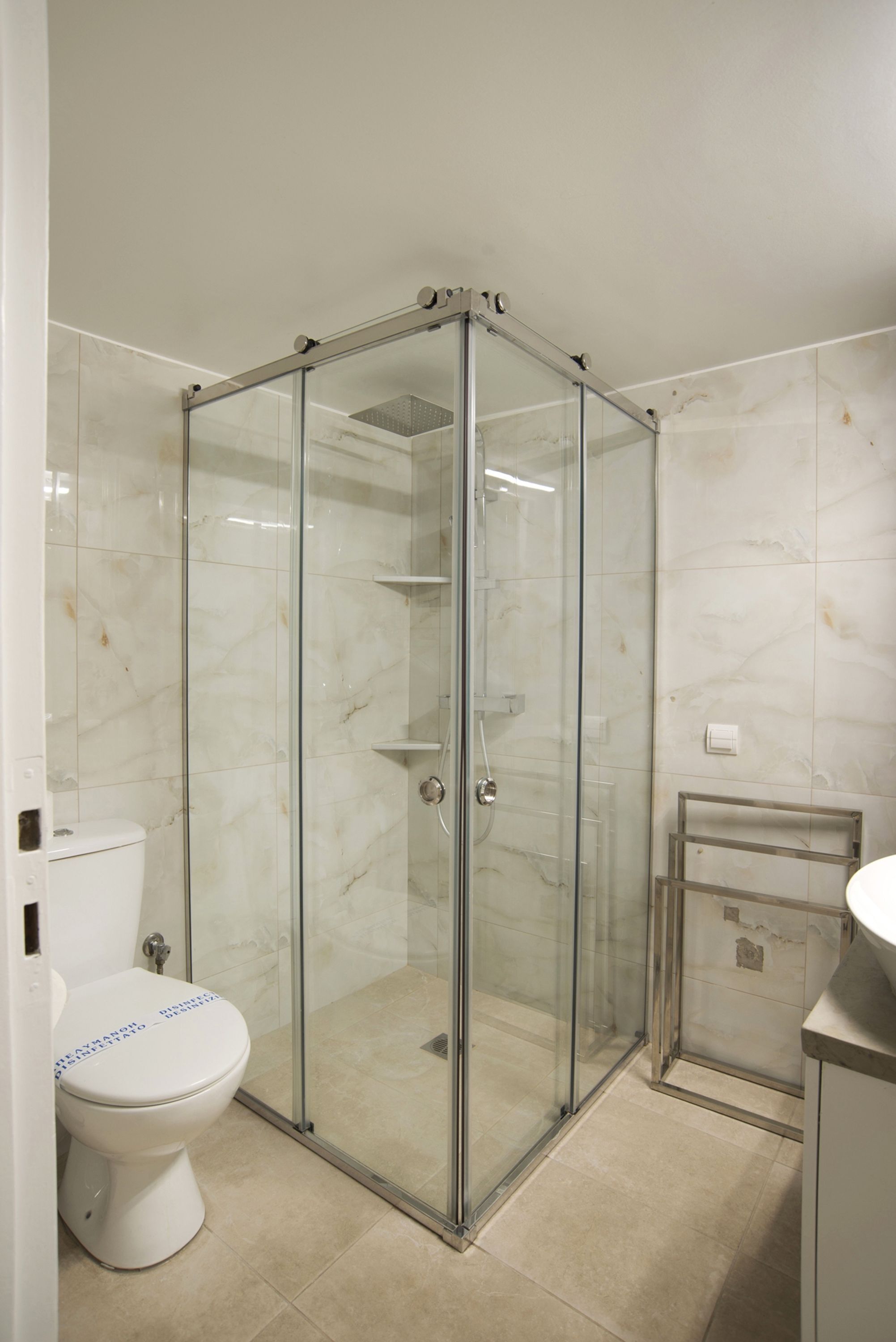 A bathroom with a glass-enclosed shower, a toilet, and a sink.