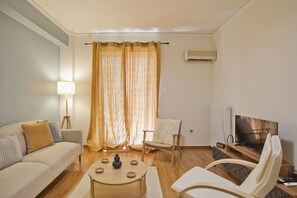 Ein Wohnzimmer mit Sofa, Sessel, Couchtisch und Fernseher.