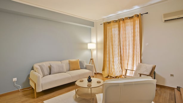 Un salon moderne comprenant un canapé, deux fauteuils, une table basse et une lampe.